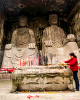 Woman honoring ancestors in front of carved Buddhas, Mount Beishan