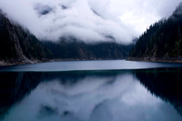 early morning fog on mountains with reflection in lake